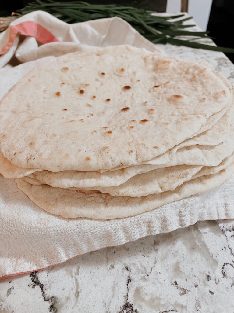 Pile of sourdough flour tortillas on a kitchen towel