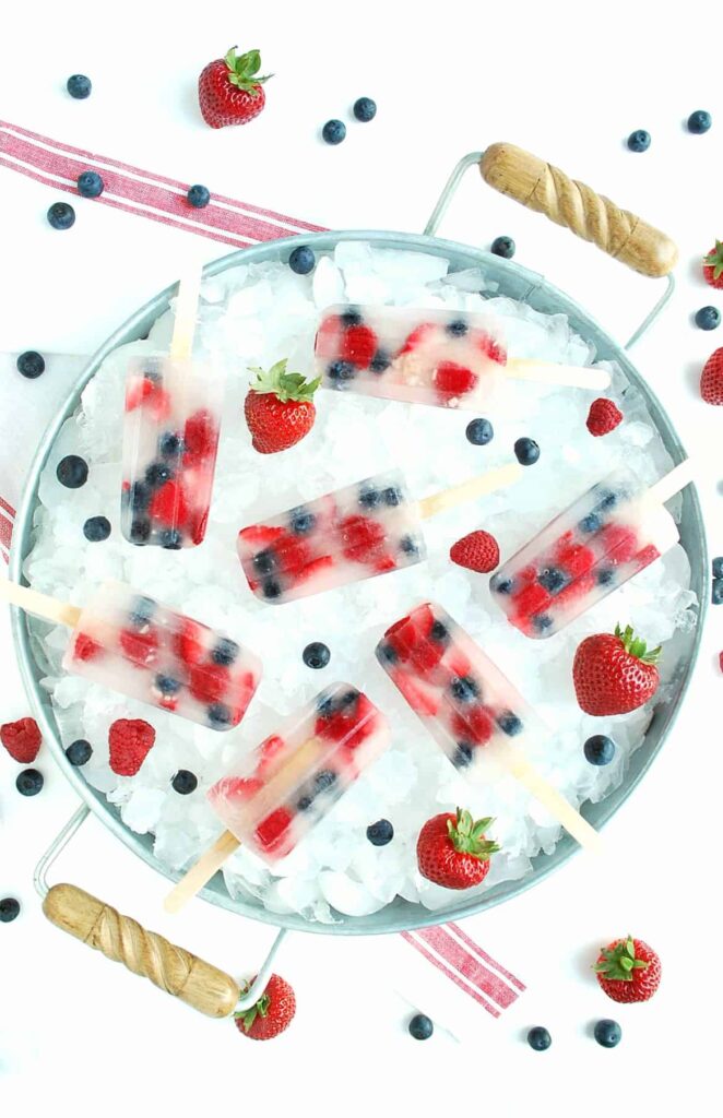 Image of clear popsicles with strawberries, raspberries, and blueberries suspended within.